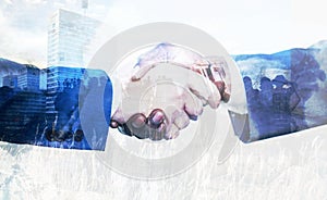 Business people shaking hands as symbol for partnership over city and nature landscape background