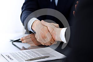 Business people shaking hands after contract signing at the glass desk in modern office. Unknown businessman with