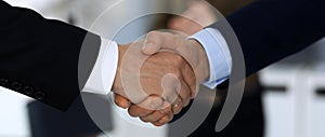 Business people shaking hands after contract signing at the glass desk in modern office. Unknown businessman, male