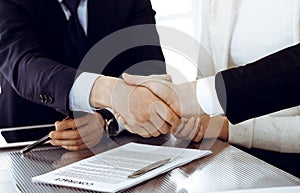 Business people shaking hands after contract signing in modern office. Teamwork, partnership and handshake concept