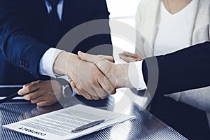 Business people shaking hands after contract signing in modern office. Teamwork, partnership and handshake concept