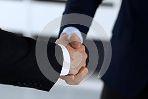 Business people shaking hands after contract signing in modern office. Unknown businessman, male entrepreneur with