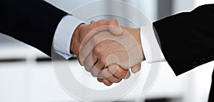 Business people shaking hands after contract signing while standing in a modern office. Teamwork and handshake concept