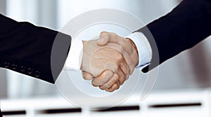 Business people shaking hands after contract signing while standing in a modern office. Teamwork and handshake concept