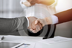 Business people shaking hands finishing contract signing in sunny office, close-up. Handshake and marketing