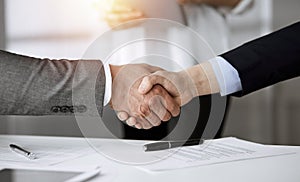 Business people shaking hands finishing contract signing in sunny office, close-up. Handshake and marketing