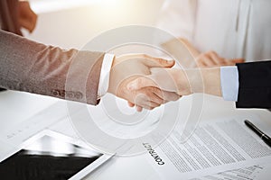 Business people shaking hands finishing contract signing in sunny office, close-up. Handshake and marketing