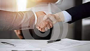 Business people shaking hands finishing contract signing in sunny office, close-up. Handshake and marketing