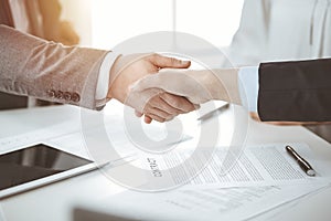 Business people shaking hands finishing contract signing in sunny office, close-up. Handshake and marketing