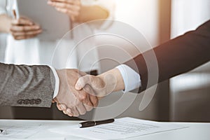 Business people shaking hands finishing contract signing in sunny office, close-up. Handshake and marketing