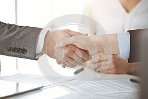 Business people shaking hands finishing contract signing in sunny office, close-up. Handshake and marketing