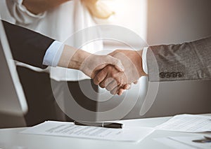 Business people shaking hands finishing contract signing in sunny office, close-up. Handshake and marketing