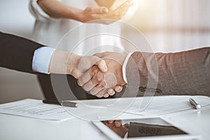 Business people shaking hands finishing contract signing in sunny office, close-up. Handshake and marketing