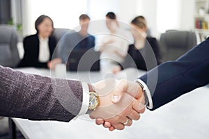 Business people shaking hands finishing a meeting in the background of their work team