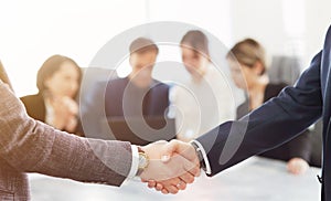 Business people shaking hands finishing a meeting in the background of their work team