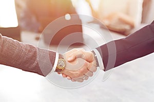 Business people shaking hands finishing a meeting in the background of their work team