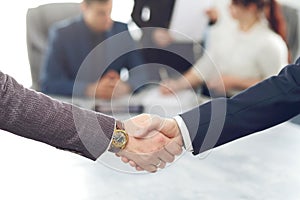 Business people shaking hands finishing a meeting in the background of their work team