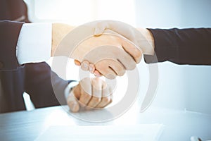 Business people shaking hands finishing up meeting or negotiation in sunny office. Business handshake and partnership