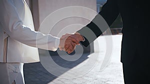 Business people shaking hands. Handshake between business man and business woman outdoors by business office building.