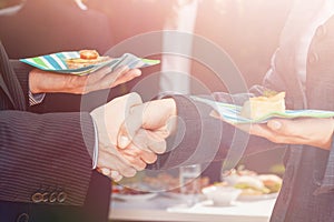 People shaking hands after making deal during business lunch