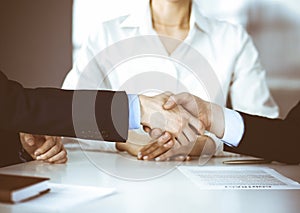 Business people shaking hands at meeting or negotiation, close-up. Group of unknown businessmen, and a woman on the