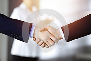 Business people shaking hands at meeting or negotiation, close-up. Group of unknown businessmen and a woman stand