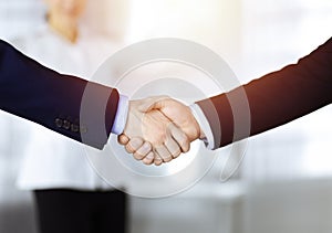 Business people shaking hands at meeting or negotiation, close-up. Group of unknown businessmen and a woman stand