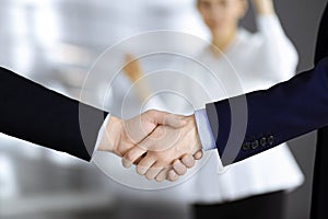 Business people shaking hands at meeting or negotiation, close-up. Group of unknown businessmen and a woman standing in