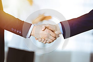 Business people shaking hands at meeting or negotiation, close-up. Group of unknown businessmen and a woman standing in