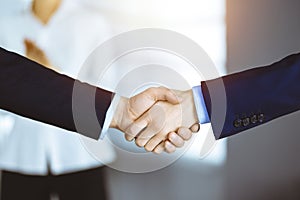 Business people shaking hands at meeting or negotiation, close-up. Group of unknown businessmen and a woman standing in