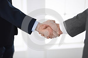 Business people shaking hands at meeting or negotiation in modern office, close-up. Teamwork, partnership and handshake