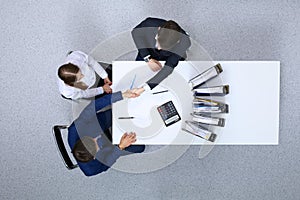 Business people shaking hands at meeting, view from above. Bookkeeper or financial inspector making report, calculatin