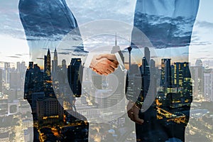 Business people shaking hands on night city background. Teamwork, success and partnership concept. Double exposure