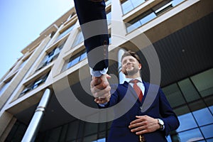 Business people shaking hands outside modern office building.