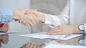 Business people shaking hands over contract agreement and financial papers at the glass table. Professional handshake