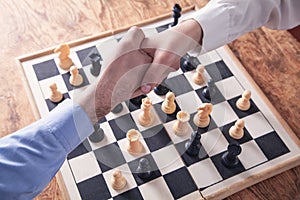 Business people shaking hands. Playing chess game