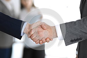 Business people shaking hands while standing with colleagues after meeting or negotiation, close-up. Group of unknown