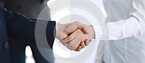 Business people shaking hands while standing with colleagues after meeting or negotiation, close-up. Group of unknown