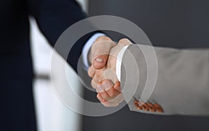 Business people shaking hands while standing with colleagues after meeting or negotiation, close-up. Group of unknown