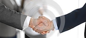 Business people shaking hands while standing with colleagues after meeting or negotiation, close-up. Group of unknown