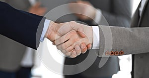 Business people shaking hands while standing with colleagues after meeting or negotiation, close-up. Group of unknown