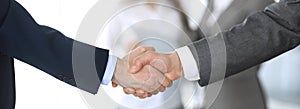 Business people shaking hands while standing with colleagues after meeting or negotiation, close-up. Group of unknown