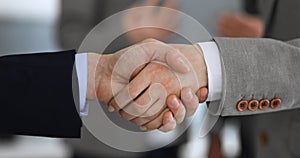 Business people shaking hands while standing with colleagues after meeting or negotiation, close-up. Group of unknown