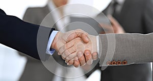 Business people shaking hands while standing with colleagues after meeting or negotiation, close-up. Group of unknown