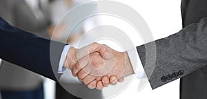 Business people shaking hands while standing with colleagues after meeting or negotiation, close-up. Group of unknown