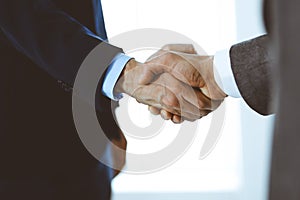 Business people shaking hands while standing with colleagues after meeting or negotiation, close-up. Group of unknown