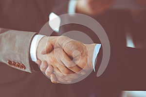 Business people shaking hands while standing with colleagues after meeting or negotiation, close-up. Group of unknown