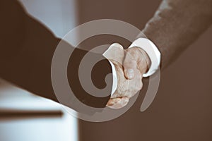 Business people shaking hands while standing with colleagues after meeting or negotiation, close-up. Group of unknown