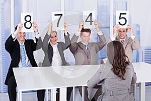 Business people showing score cards in front of female candidate