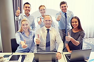 Business people showing thumbs up in office
